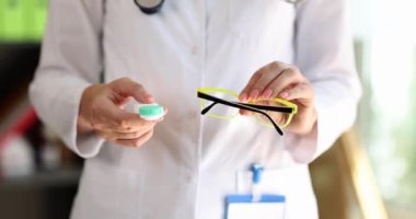 Kadın bir doktor. Gözlük ve kontakt lens tutuyor. Yakın plan. Görüş için aksesuar seçimini kavra
