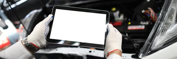 Close-up of mechanic worker using tablet for diagnostics of technical condition of vehicle. Handyman applying digital tablet at car service. Maintenance concept