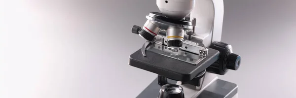 Close-up of modern microscope tool for laboratory research on grey background, magnifying device for precise results of research or experiment. Scientific appliance