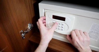 Yetişkin adam otel odasında kasa kullanıyor ve gizli kodu çeviriyor. Dolapta ve finansal güvencede güvende.