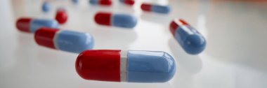 Close-up of red and blue pills on glass surface. Medication in capsules. Pharmacy, antibiotics or vitamins. Medicine, healthcare and treatment concept