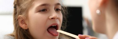 Portrait of pediatrician checking girls hurting throat with stick. Child open mouth for check up. Female doctor use tool for examination health. Medicine concept