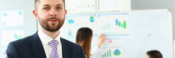 Портрет бизнесмена в офисе в презентабельном костюме, коллеги обсуждают аналитические данные и статистику. Успех, человеческие ресурсы, бизнес, концепция карьерного роста