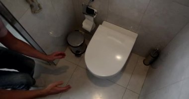 Adam tuvaletin kapağını açıyor ve ağır çekimde kusuyor. Mide bulantısı ve kusma mide iltihabı belirtisidir. 