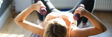 Spor salonundaki halterlerle çalışan bir kadının en iyi görüntüsü. Genç bir kadın dambıllarla spor yapıyor. Sağlıklı yaşam tarzı kavramı