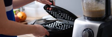 Close-up of woman preparing belgian waffle maker in kitchen. Waffle iron in kitchen. Preparing homemade waffles