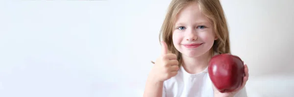 一个小女孩手里拿着红苹果 伸出大拇指的画像 健康食品和维生素 — 图库照片