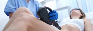 Doctor doing laser hair removal of legs of female client closeup. Beauty industry concept