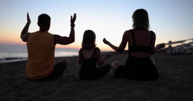 Aile, plajda birlikte vakit geçirir ebeveynler ve çocuklar meditasyon yapar ve yoga yaparlar. Aile uyumu ve rahatlama