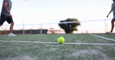 Tenis kortunun ortasında erkek ve kadın tenisçiler top ve ağın arka planına karşı el sıkışıyorlar. Tenis turu ve tenis adabı kavramının tamamlanması