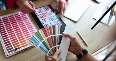 Tasarım stüdyosunda tasarımcı ve müşteriyle tanışıp ürünleri renklendirmek ve markalaştırmak. Renk örnekleri ve tablet bilgisayarlı yaratıcı çalışma alanı