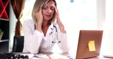 İş yerinde başı ağrıyan yorgun kadın doktor. Yorgun bir terapist doktor. Baş ağrısı çekiyor ve acı çekiyor.