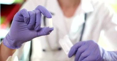 Eldivenli doktor ellerinde tıbbi mumlar ve vajinal haplar tutuyor. Prostat iltihabı ve zührevi hastalıkların tedavisi