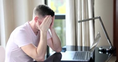 Evde dizüstü bilgisayarla çalışıp baş ağrısına dokunmaktan yorgun düşmüş. Migreni olan ve aşırı çalışmaktan, modern teknoloji ve sağlık kavramından bitap düşmüş bir adam.