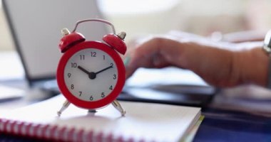 Freelancer yöneticisi çalar saatin yanındaki dizüstü bilgisayarda çalışıyor. Uzaktan çalışma ve fazla mesai için zaman yönetimi ve planlama