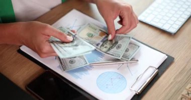 Kadın, aylık gider vergilerini hesaplıyor banka bakiyeleri ve nakit ödemeleri. İş kadını ofis masasında para sayıyor ve yozlaşmış para sistemi.