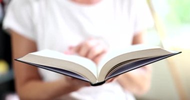 Kitap okuyor ve sayfaları kapatıyor. Kadın elleri kitabı tutuyor ve sayfaları çeviriyor.