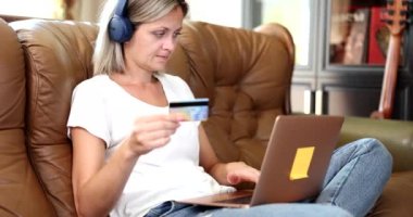 Kulaklık takan ve banka kartı olan bir kadın internet üzerinden dil kurslarına para ödüyor. Uzaktan ödeme ve sipariş malları İnternet 'te
