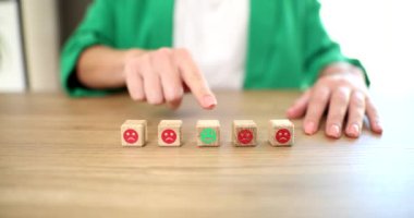 Müşteri memnuniyeti araştırması konsepti. Müşteri eli geri bildirim anketi ve iş için tahta küpten gülen surat seçiyor.