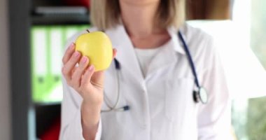 Doktor diyetisyen sarı elmayı kendine yakın tutuyor. Doktor elleri meyve, sağlık ve vitamin sembolü tutar.