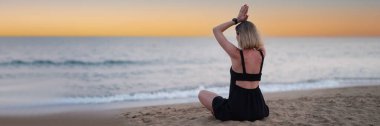 Gün batımında deniz kenarında yoga yapan bir kadın. Sakinlik ve rahatlama konsepti