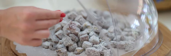 Woman hand taking piece of Turkish delight with coconut closeup. Turkish sweets concept