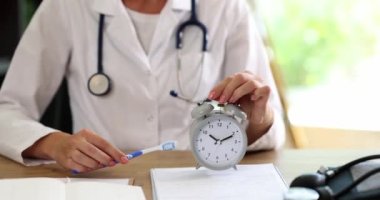 Kadın dişçi klinikte diş fırçası ve çalar saat tutuyor. Zaman ve kurallar ağız sağlığını önemser