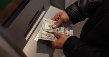 Gece geç saatlerde ATM 'nin yanında dolar sayan bir adam 4K' lık filmi yavaş çekimde yakalıyor. Finansal işlem kavramı 