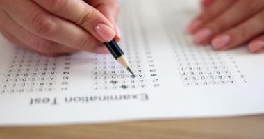 Kadın elinde kalemle sınav sorularına cevap veriyor. Test konsepti işe alınıyor