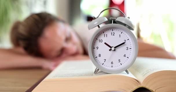 女性は本を読むために眠りに落ち テーブルの上で目覚まし時計 時間学習教育の怠惰と動機 — ストック動画