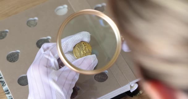 手袋をしている人は虫眼鏡を通してコインを見る 貨幣に関する数学的 詳細な情報 — ストック動画