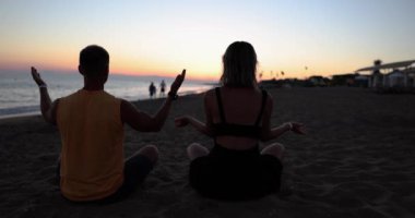 Sahilde birlikte fitness yogası yapan aile çifti. Deniz günbatımında güç ve denge için akroyoga öğesi
