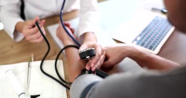 Kadın doktor kalp atış hızı monitörüyle yüksek tansiyon ve kalp atış hızını ölçer. Kardiyolog, hastaya tonometre ile kan basıncını ölçer.