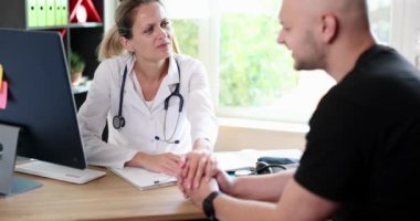 Dost canlısı kadın doktorun elleri cesaretlendirmek ve sempati duymak için erkek hasta elini tutuyor. Ortaklık güveni ve tıbbi etik kavramı