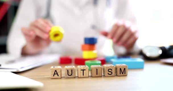 医師は多色のキューブとテキスト自閉症を手に保持しています 自閉症の子供の開発と子供の状態を改善し 世界中に適応するのに役立ちます — ストック動画