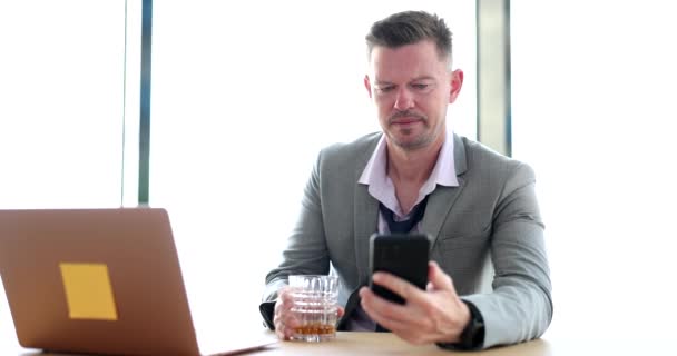 Zdenerwowany Biznesmen Pijący Alkohol Miejscu Pracy Patrzący Smartfona Złe Wieści — Wideo stockowe
