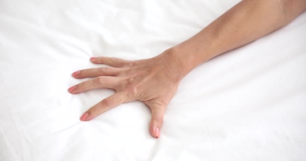 女の手は情熱的にベッドの上にシートをクラッチ ベッドの上で若い女性の近さ — ストック動画