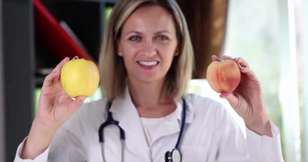 微笑的营养师医生拿着苹果和桃果实 水果风味 健康益处和维生素 — 图库视频影像