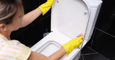 Eldivenli kadın elleri ve banyoda tuvalet temizleme kabı. Banyoda temizlik ve hijyen.
