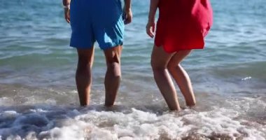 Deniz kıyısında zıplayan bir adam ve bir kadın, yakın plan. Denizde eğlence, rahatlama.