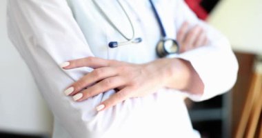 Beyaz üniformalı doktor ellerini çaprazladı, yakın plan, yavaş çekim. Tıp uzmanı, meslek.