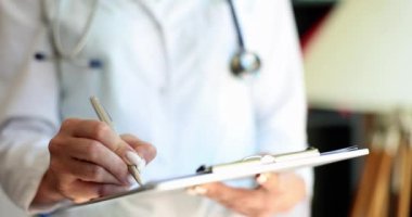 Beyaz üniformalı doktor bir kalem yazıyor, yakın plan, yavaş çekim. Tıbbi teşhis, ilaç tedavisi