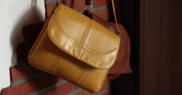 新的黄色和棕色的妇女袋挂在墙上 动作缓慢 走廊里的皮包 — 图库视频影像