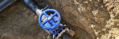 Yerdeki kanalizasyon sistemini kontrol etmek için mavi musluk. Siperdeki su boruları. Su dağıtım manifoldu.