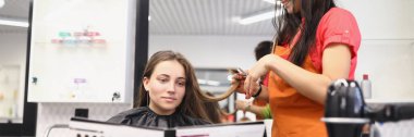Portrait of client look in folder with hair colour samples, hairdresser work on hairstyle. Master ready to change client image. Beauty, barbershop concept