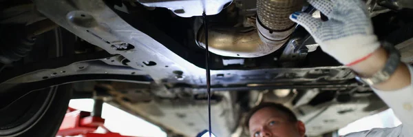 Portrait of mechanic man change oil under auto, car maintenance service, oil dripping. Qualified worker fix your vehicle. Pit stop, repair, service concept
