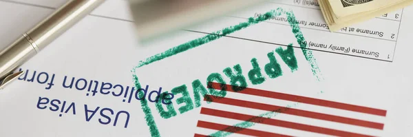 Close-up of green approved stamp on document, visa application form, hand stamping approved on sheet. Permit, authority, resident, allowed to enter concept