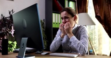 Endişeli iş kadını bilgisayar ekranına bakıyor ve tırnaklarını yiyor. 4K film yavaş çekim. İş konseptinde stres
