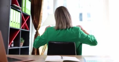 Uzun çalışma saatlerinden sonra ergonomik ofis sandalyesinde elleri başının arkasında uzanan kadının dikiz görüntüsü. İş kadını ara veriyor. Basit egzersizler yapıyor. İş yerinde oturuyor.