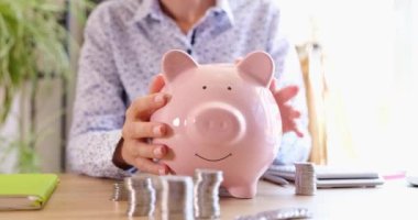 Başarılı bir kadın kumbarayı sallıyor. Finansal gelir ve tasarruftan memnun. Kârlı nakit yatırımı
